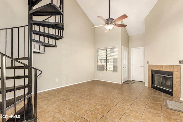 unfurnished living room with a fireplace, light tile patterned floors, high vaulted ceiling, and ceiling fan