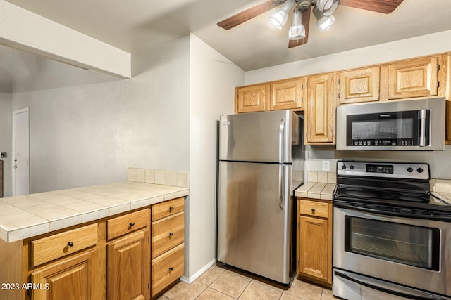 kitchen featuring ceiling fan, appliances with stainless steel finishes, tile counters, and light tile patterned flooring