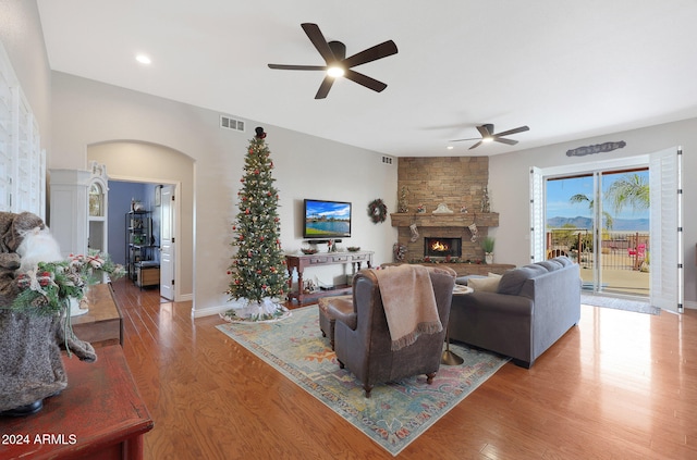 living room featuring ceiling fan, a fireplace, and wood-type flooring