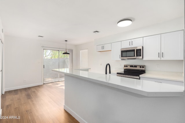 kitchen featuring white cabinets, pendant lighting, kitchen peninsula, light hardwood / wood-style flooring, and appliances with stainless steel finishes