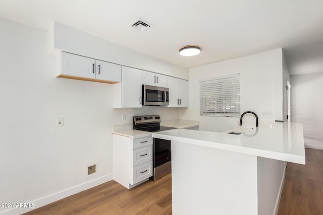 kitchen with hardwood / wood-style flooring, sink, white cabinets, kitchen peninsula, and stainless steel appliances