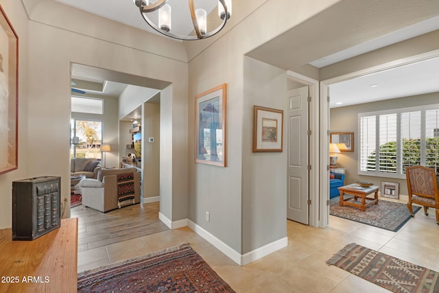 hallway with light tile patterned floors and a notable chandelier