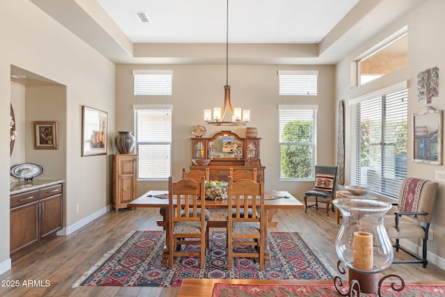 dining area featuring a tray ceiling, dark hardwood / wood-style flooring, and a notable chandelier