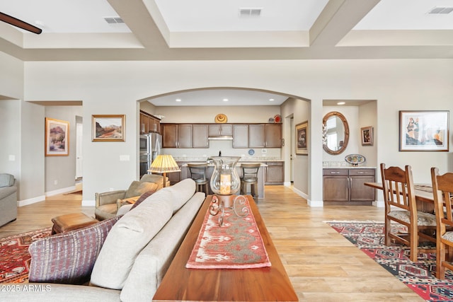 living room featuring beam ceiling, coffered ceiling, and light wood-type flooring