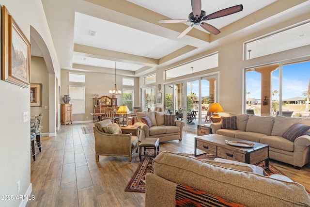 living room featuring a raised ceiling, ceiling fan with notable chandelier, french doors, and light hardwood / wood-style flooring