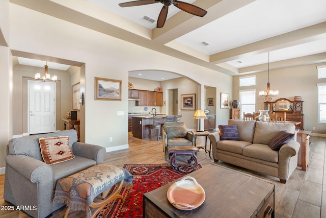 living room with ceiling fan with notable chandelier and light hardwood / wood-style floors