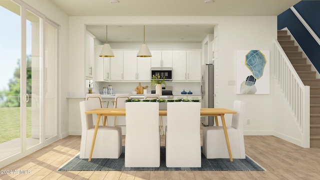 kitchen featuring light hardwood / wood-style floors, white cabinets, pendant lighting, and appliances with stainless steel finishes