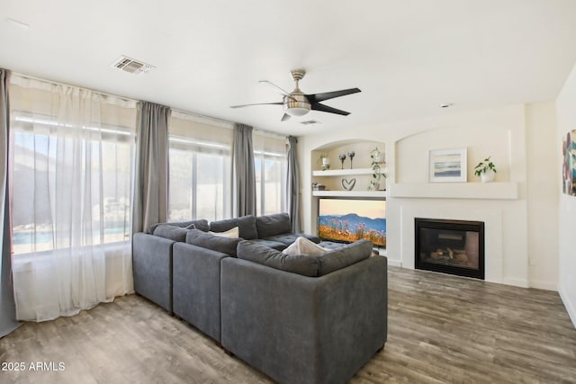 living room featuring ceiling fan, wood-type flooring, and built in features