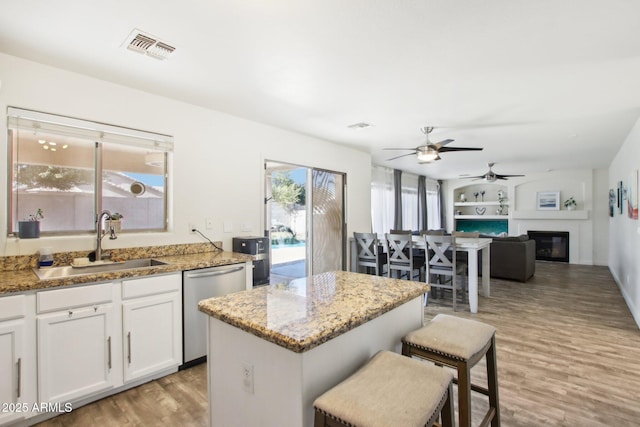 kitchen featuring light stone countertops, white cabinetry, dishwasher, and sink