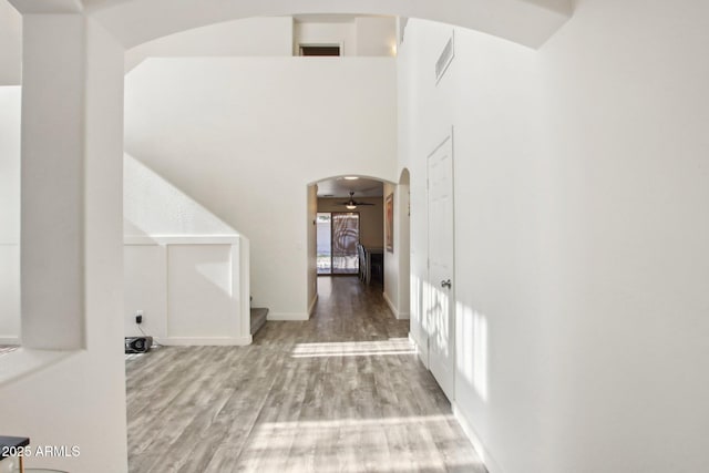 hall with a high ceiling and light hardwood / wood-style floors