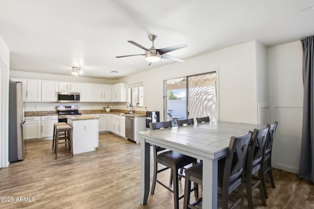 kitchen featuring white cabinets, appliances with stainless steel finishes, a kitchen island, a kitchen bar, and sink