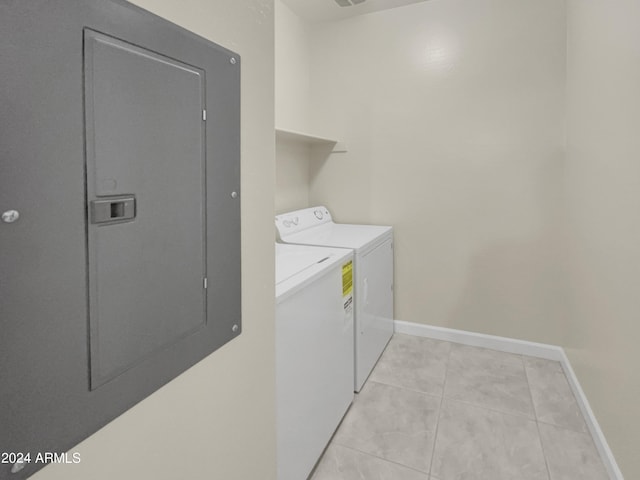 laundry room with washer and dryer, light tile patterned flooring, and electric panel