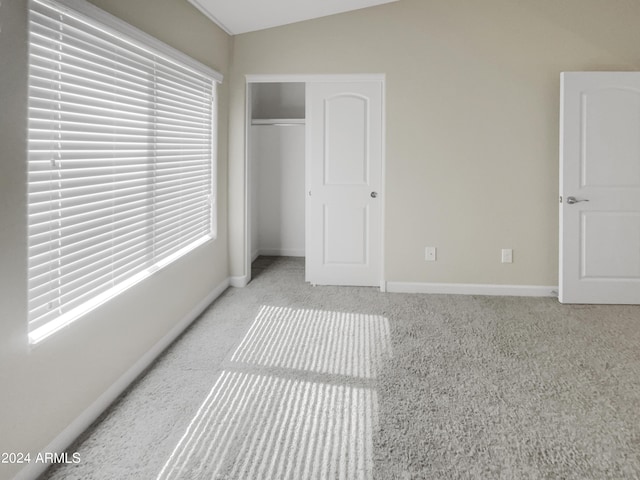 bedroom featuring light colored carpet, lofted ceiling, and a closet