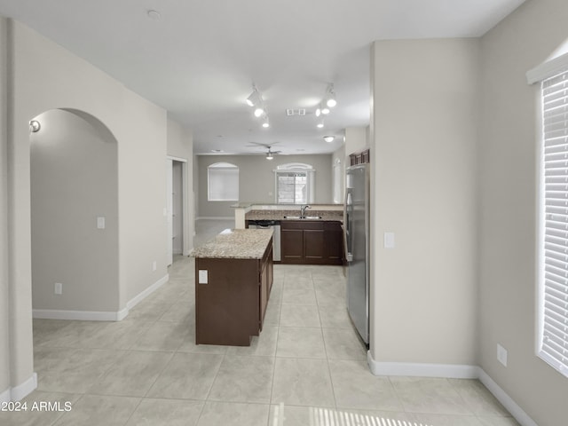 kitchen with ceiling fan, sink, a center island, light tile patterned floors, and appliances with stainless steel finishes