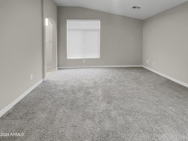 carpeted spare room featuring vaulted ceiling