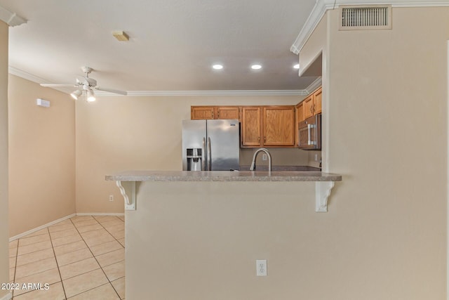 kitchen with a breakfast bar, light tile patterned floors, stainless steel appliances, and ornamental molding