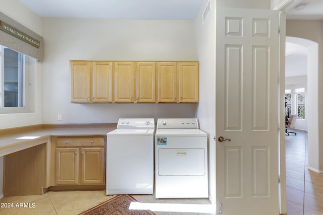 laundry area with washer and dryer, light tile patterned floors, and cabinets