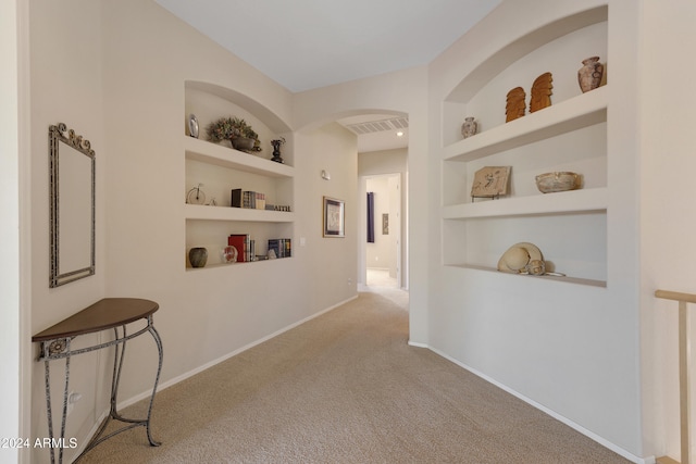 hallway featuring light colored carpet and built in shelves