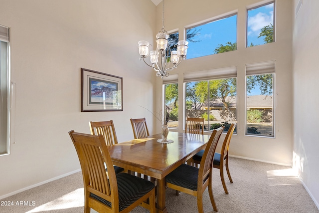 carpeted dining area with a towering ceiling, a chandelier, and a healthy amount of sunlight