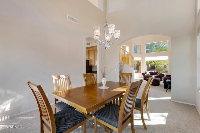 carpeted dining room with a high ceiling and a chandelier