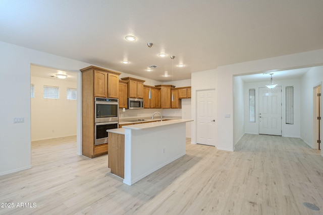 kitchen featuring brown cabinetry, light wood-style floors, light countertops, and stainless steel appliances