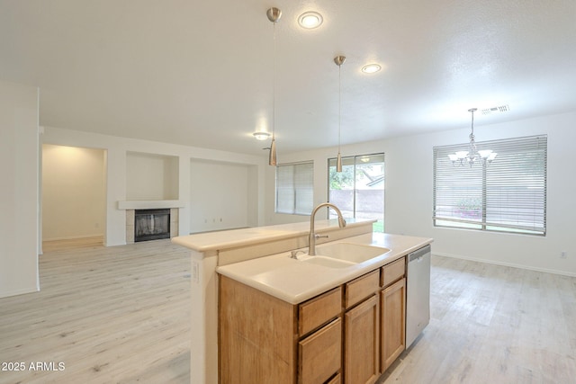 kitchen featuring a tiled fireplace, visible vents, light wood-style flooring, a sink, and stainless steel dishwasher