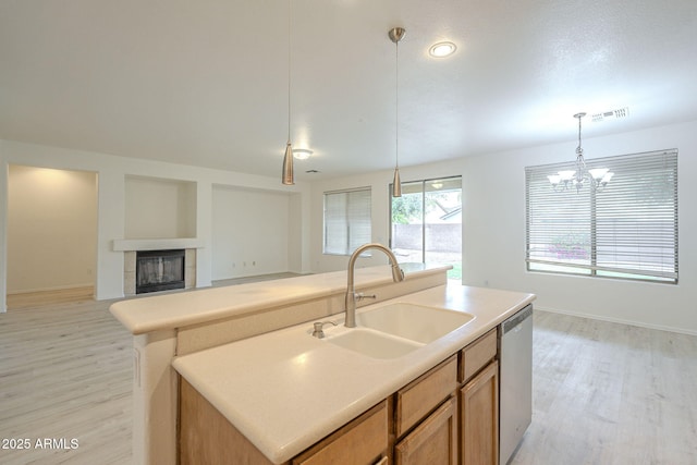 kitchen with visible vents, a tile fireplace, a sink, pendant lighting, and stainless steel dishwasher