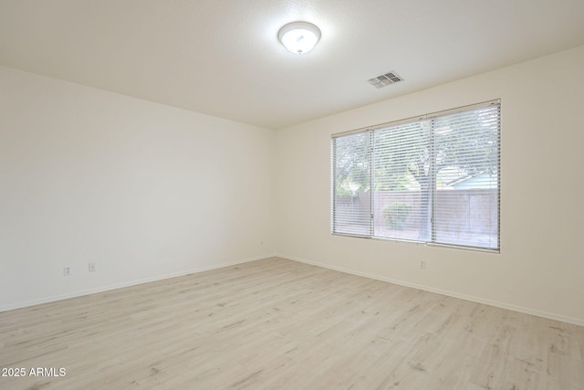 empty room featuring baseboards, visible vents, and light wood-type flooring