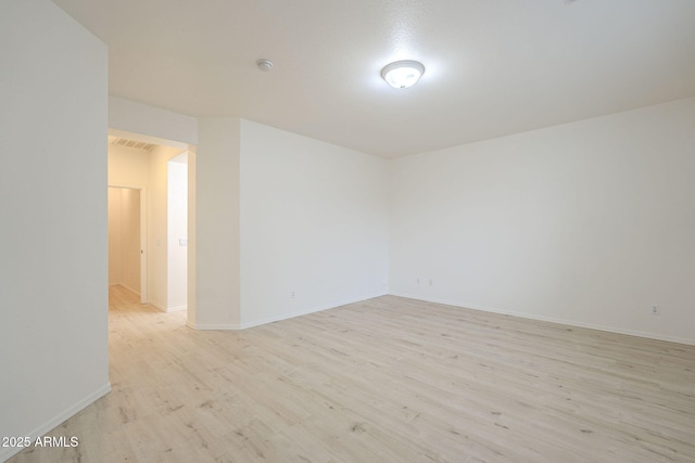 unfurnished room featuring visible vents, light wood-type flooring, and baseboards