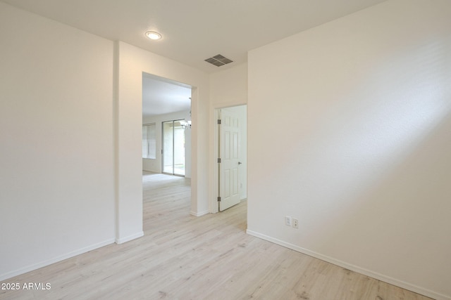 spare room featuring light wood-type flooring, visible vents, and baseboards