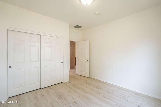 unfurnished bedroom with visible vents, baseboards, a closet, and light wood finished floors