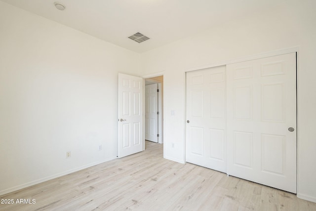 unfurnished bedroom featuring a closet, visible vents, light wood-style flooring, and baseboards