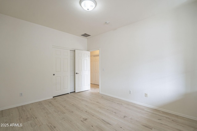 empty room featuring light wood finished floors, visible vents, and baseboards