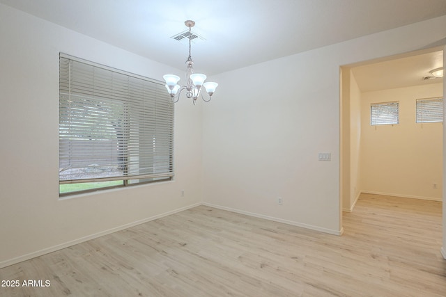 spare room featuring wood finished floors, visible vents, and baseboards