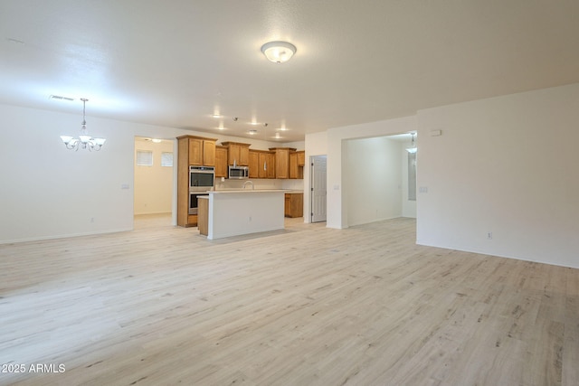 unfurnished living room featuring visible vents, baseboards, a notable chandelier, and light wood-style flooring