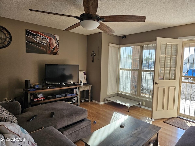 living room featuring light wood-type flooring, ceiling fan, and a textured ceiling