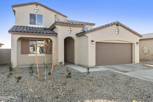 mediterranean / spanish house featuring a tile roof, driveway, stucco siding, and an attached garage