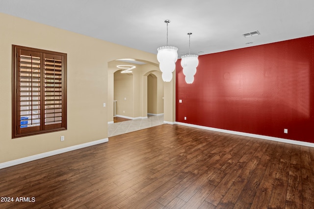 unfurnished dining area featuring a notable chandelier and hardwood / wood-style flooring