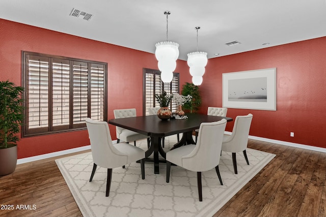 dining room featuring baseboards, visible vents, and wood finished floors