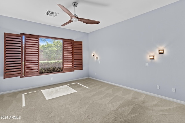 carpeted empty room with baseboards, ceiling fan, and visible vents