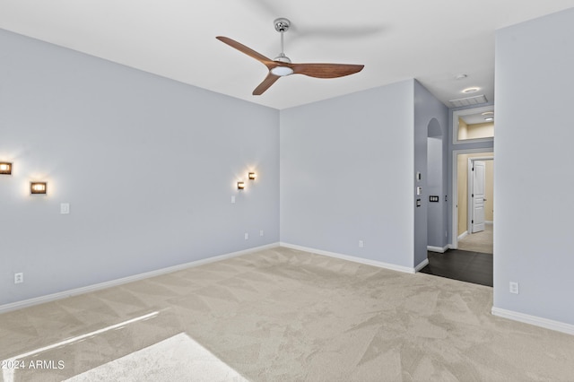 spare room with baseboards, carpet flooring, ceiling fan, and arched walkways
