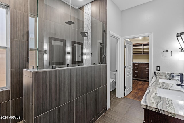 bathroom with double vanity, toilet, a sink, and walk in shower