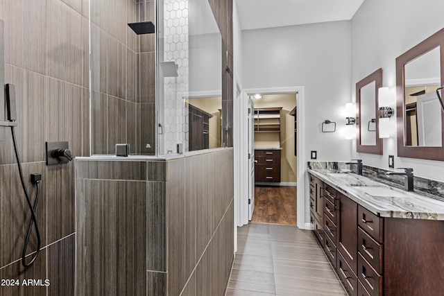 bathroom featuring baseboards, double vanity, a sink, and walk in shower