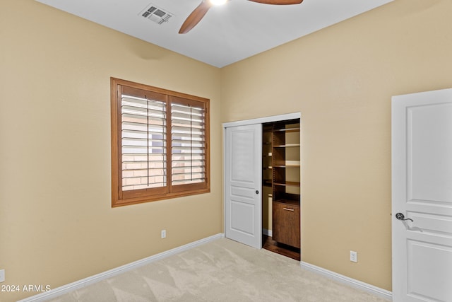 unfurnished bedroom featuring ceiling fan, a closet, and light carpet