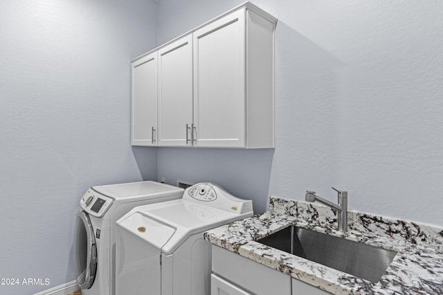 laundry room with independent washer and dryer, a sink, cabinet space, and a textured wall