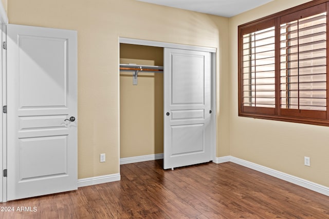 unfurnished bedroom with a closet, a barn door, and dark hardwood / wood-style floors