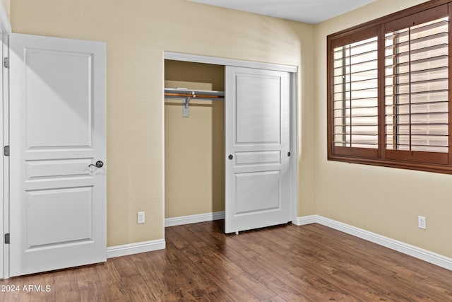 unfurnished bedroom with baseboards, a closet, and wood finished floors