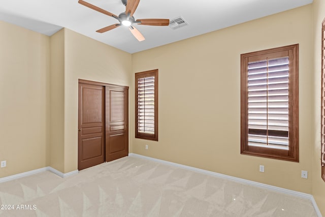 unfurnished bedroom with ceiling fan, a closet, and light carpet