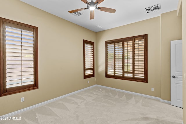 empty room with a ceiling fan, baseboards, light colored carpet, and visible vents