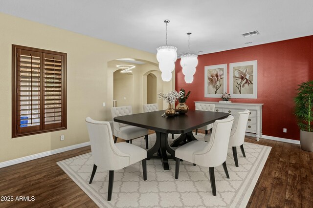 dining space featuring dark wood finished floors, arched walkways, baseboards, and visible vents